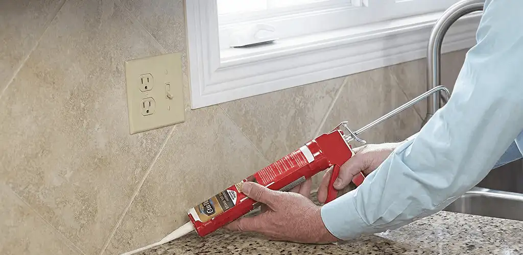 Handyman applying caulk along a kitchen backsplash and countertop seam in Green Bay, WI