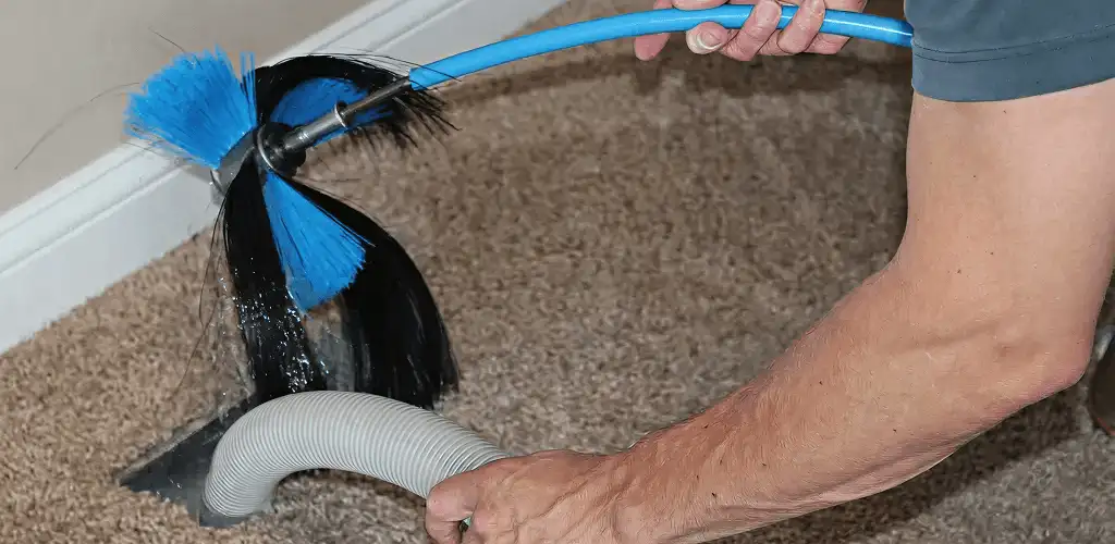 Dryer vent cleaning technician brushing lint from a vent line in Green Bay, WI