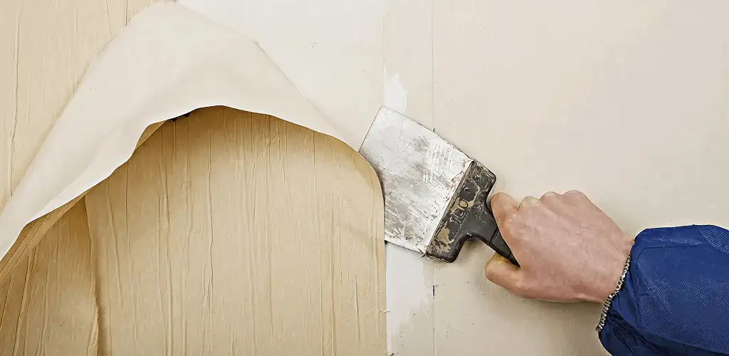 Handyman removing wallpaper with a scraper for wall preparation in Green Bay, WI