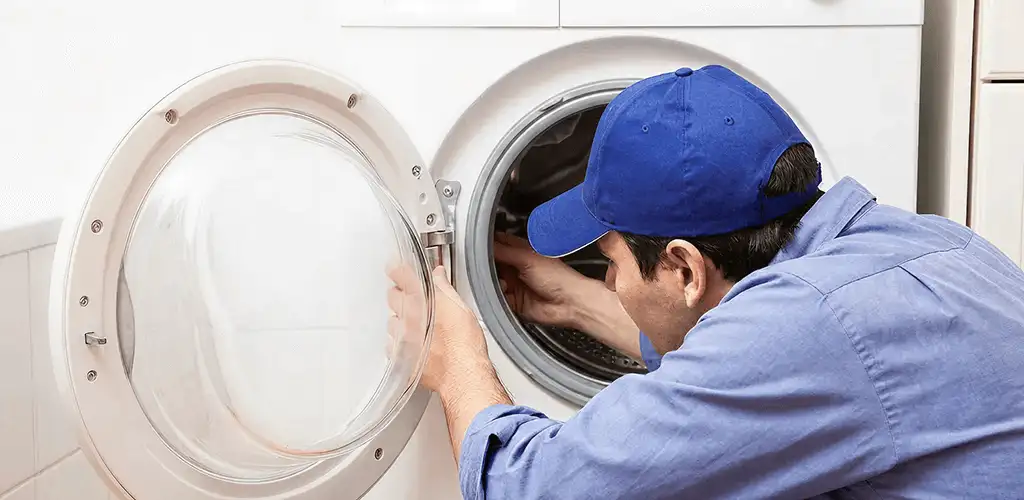 Washing machine repair handyman inspecting a front-load washer drum in Green Bay, WI
