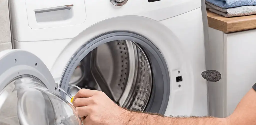 Handyman repairing a front-load washing machine and inspecting the drum in Green Bay, WI