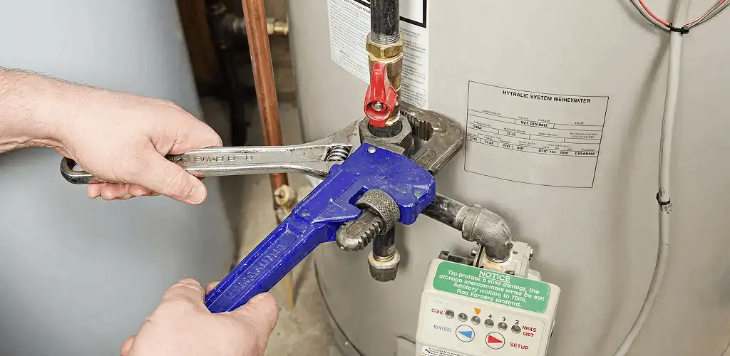 Water heater repair technician tightening the shutoff valve and supply line in Green Bay, WI